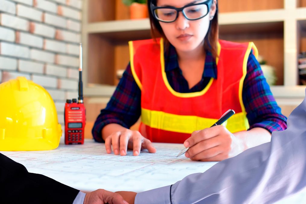 Especialista con chaleco de seguridad revisando planos y permisos